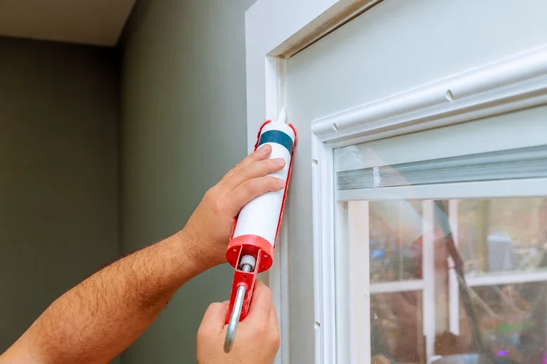 Caulk being applied along window trim